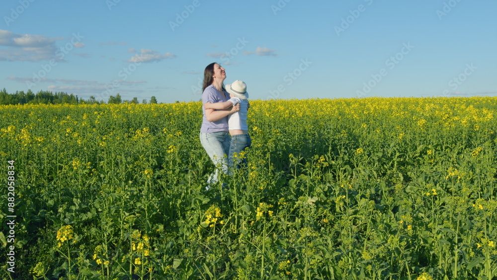 Fototapeta premium Small Boy Enjoy Playing With His Mom In A Yellow Flowering Rapeseed Field. Farmland With Yellow Flowering Rapeseed. Play On Field Outdoors.