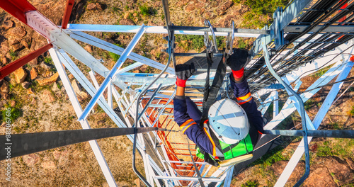 Aerial view, technician climbing on a communication tower to repair an cellular antenna for wireless internet