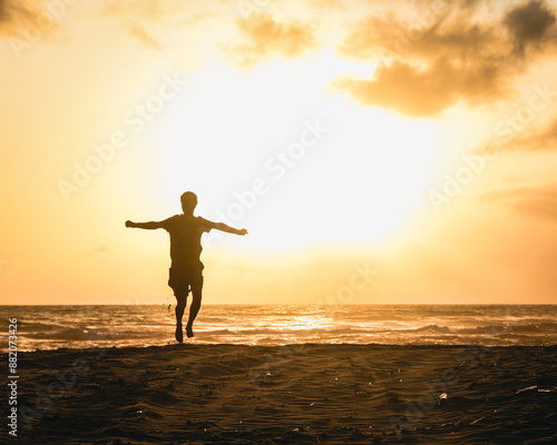 silhueta de homem não identificado correndo de braços abertos em nascer do sol na praia, no Ceará  photo