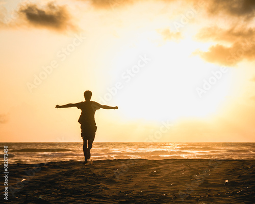 silhueta de homem não identificado correndo de braços abertos em nascer do sol na praia, no Ceará  photo