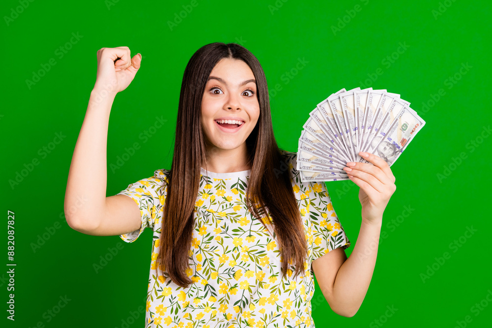 Photo portrait of pretty teen girl money fan winning wear trendy flowers print outfit isolated on green color background Photo portrait of pretty teen girl money fan winning wear trendy flowers print outfit isolated on green color background