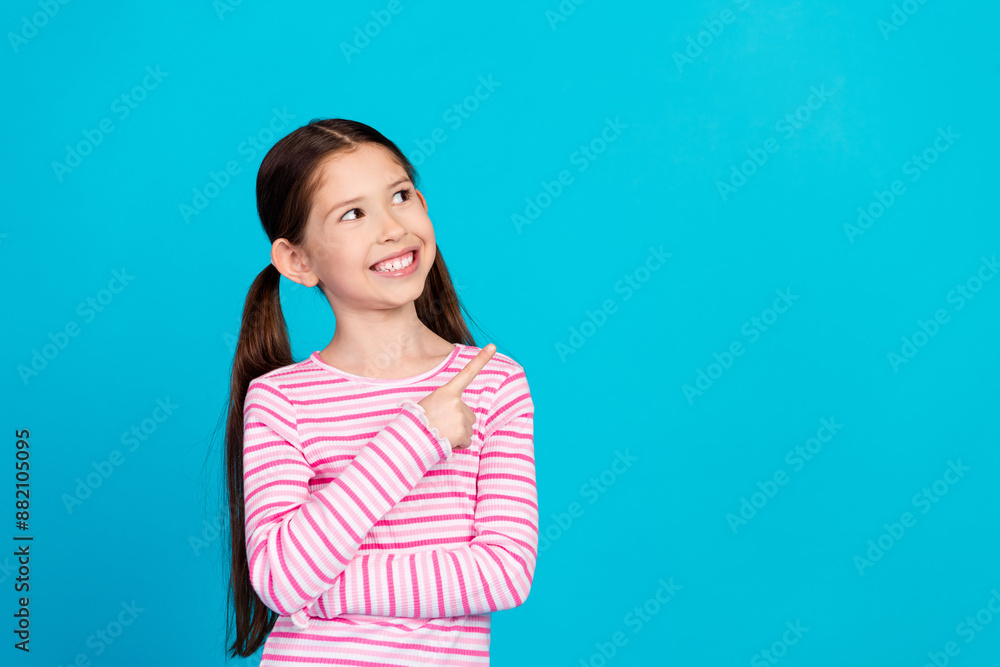 Photo of positive small girl with ponytails dressed striped shirt look directing at sale empty space isolated on blue color background Photo of positive small girl with ponytails dressed striped shirt look directing at sale empty space isolated on blue color background