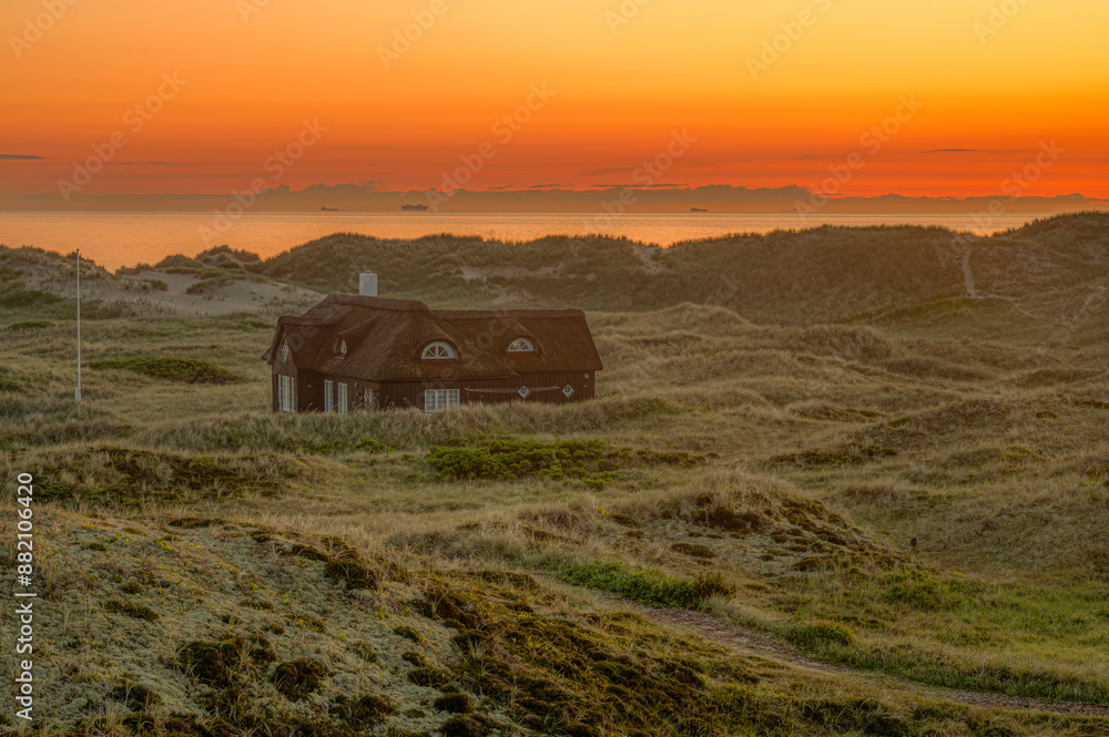lonely old house in the dunes at sunset