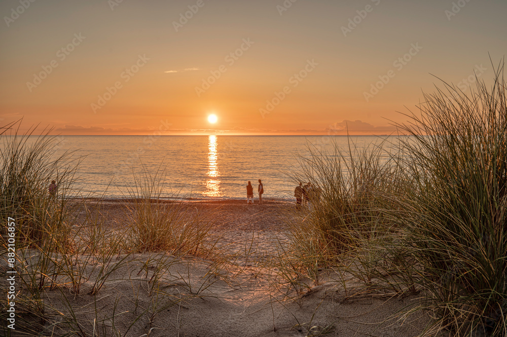 people standing on the beach watching the sunset in the sea