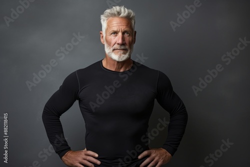 Portrait of a glad man in his 60s showing off a lightweight base layer over bare concrete or plaster wall photo