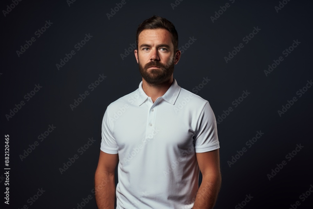 Portrait of a content man in his 30s wearing a breathable golf polo over blank studio backdrop Portrait of a content man in his 30s wearing a breathable golf polo over blank studio backdrop