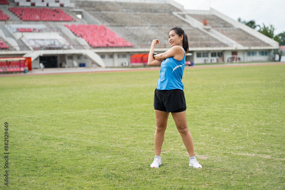 Happy Mature Asia woman runner stretching before run on racetrack Happy Mature Asia woman runner stretching before run on racetrack