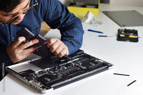 Computer technician wearing glasses, laptop motherboard repairer, using his hands to remove old battery from computer, illustration of computer technician work