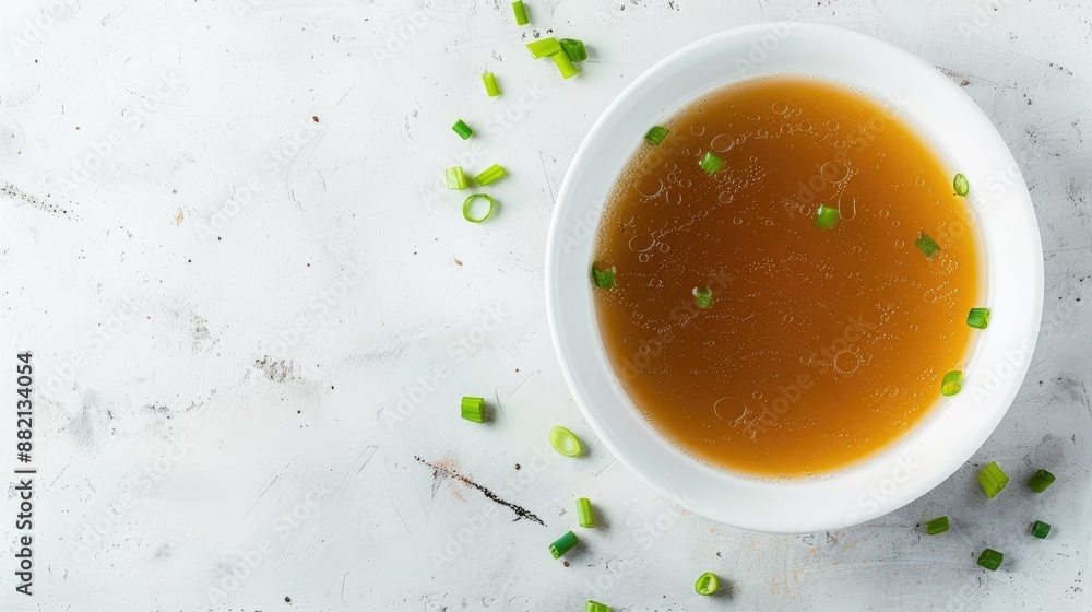Chicken broth with green onion in white bowl on white table Top view with empty space Chicken broth with green onion in white bowl on white table Top view with empty space