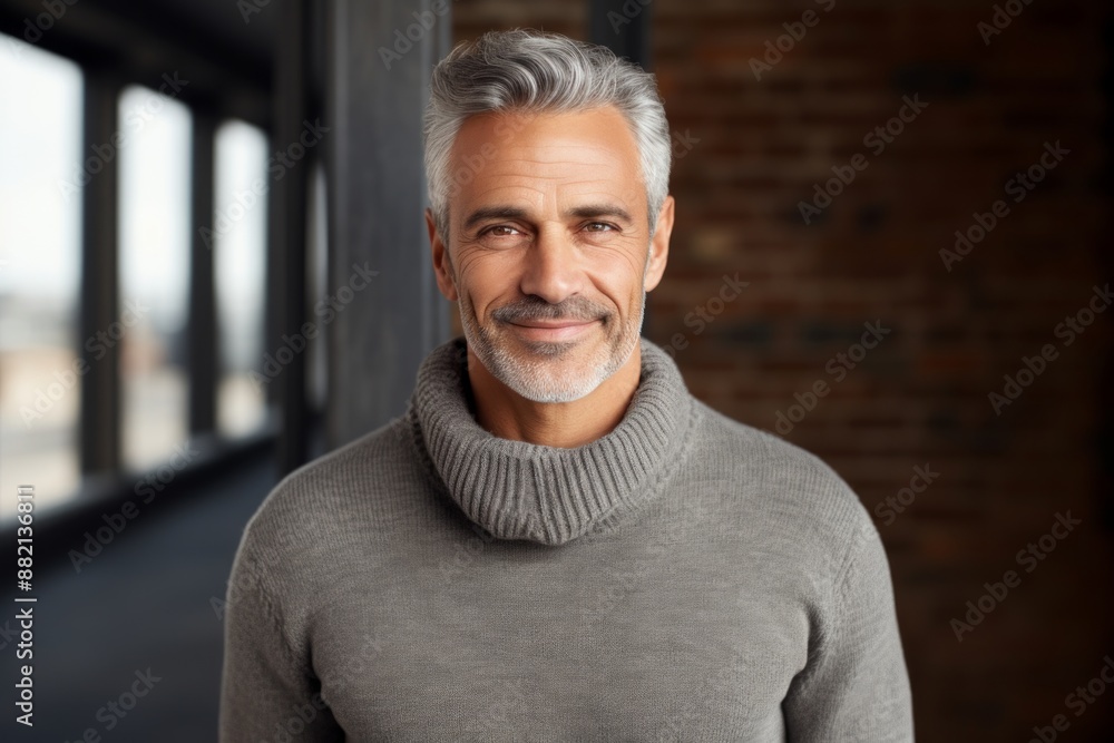 Portrait of a satisfied man in his 50s dressed in a warm wool sweater in front of empty modern loft background Portrait of a satisfied man in his 50s dressed in a warm wool sweater in front of empty modern loft background