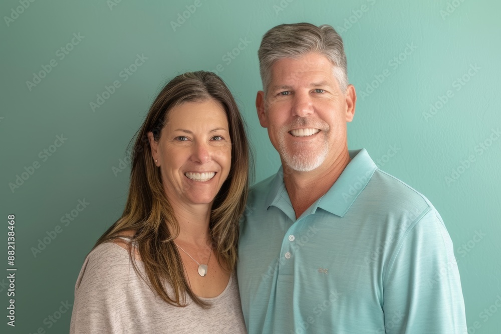 Portrait of a happy caucasian couple in their 30s wearing a breathable golf polo isolated in soft teal background Portrait of a happy caucasian couple in their 30s wearing a breathable golf polo isolated in soft teal background