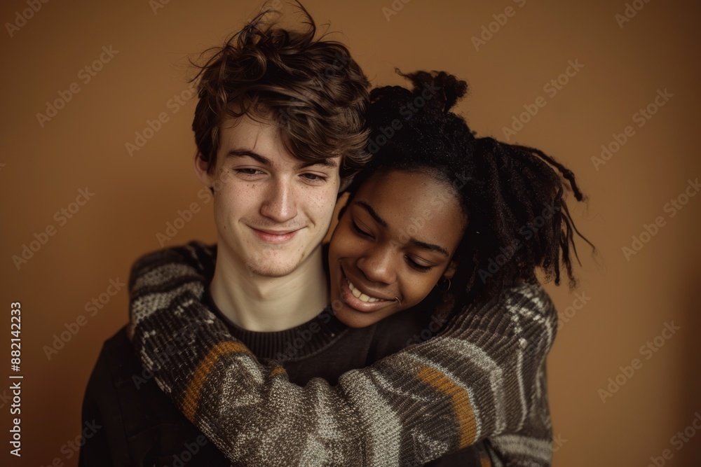 Portrait of a happy multiethnic couple in their 20s wearing a cozy sweater in front of soft brown background Portrait of a happy multiethnic couple in their 20s wearing a cozy sweater in front of soft brown background