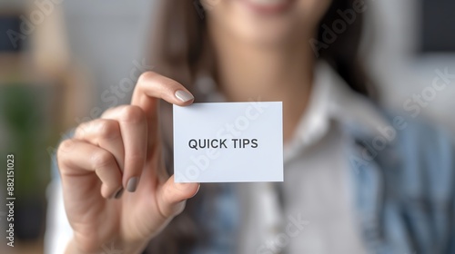Close-up of a person holding a small card with the text 'Quick Tips'. Blurred background and focus on the card.