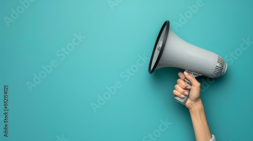 A human hand holding a sleek, modern megaphone with a solid blue backdrop and ample copy space