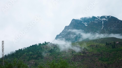 4K shot of clouds under the Himalayan mountain peaks during the monsoon season as seen from Keylong in Lahaul, Himachal Pradesh, India. Cloud under the mountain during the rainfall. Nature background. photo