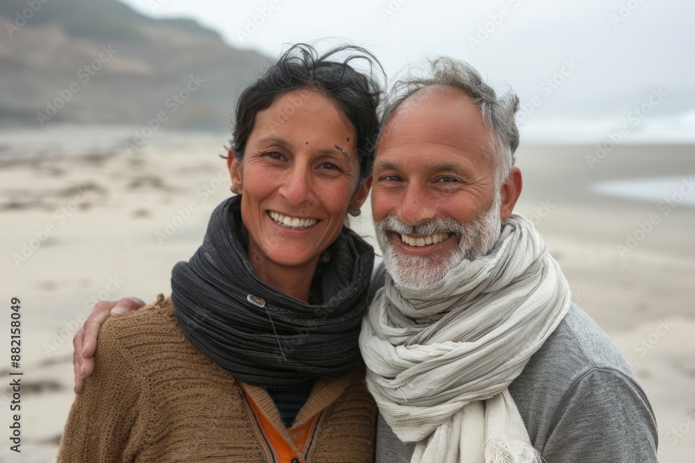 Portrait of a smiling indian couple in their 40s wearing a protective neck gaiter on sandy beach background Portrait of a smiling indian couple in their 40s wearing a protective neck gaiter on sandy beach background
