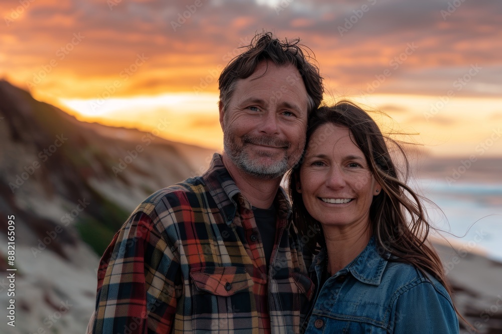Portrait of a satisfied caucasian couple in their 30s wearing a comfy flannel shirt while standing against stunning sunset beach background Portrait of a satisfied caucasian couple in their 30s wearing a comfy flannel shirt while standing against stunning sunset beach background