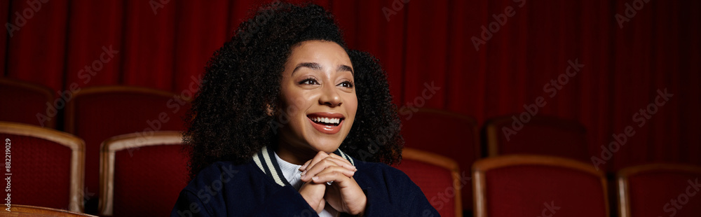 An African American woman in casual clothing watches a movie in a cinema, visibly enjoying it. An African American woman in casual clothing watches a movie in a cinema, visibly enjoying it.