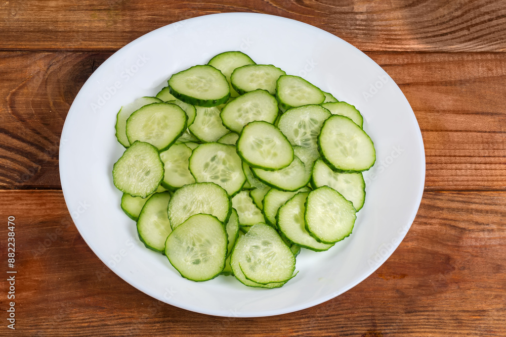 Fresh cucumbers cut into circles on dish on rustic table Fresh cucumbers cut into circles on dish on rustic table