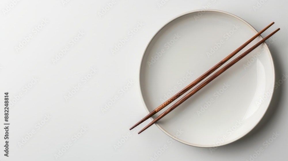 Two chopsticks on a white plate against a white wall backdrop Two chopsticks on a white plate against a white wall backdrop