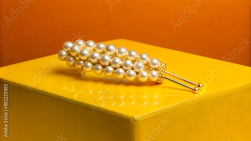 Elegant gold hair accessory with lustrous pearls on a vibrant yellow background photo