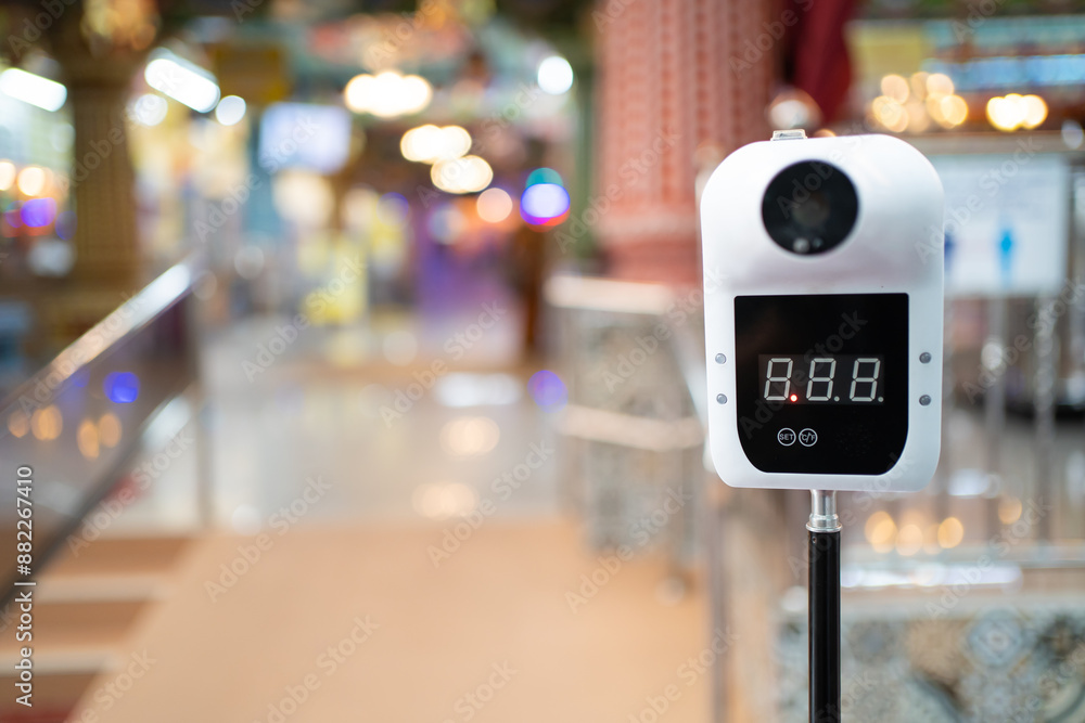 A digital, smart, non-contact, hands-free forehead infrared thermometer with a blurred background. A digital, smart, non-contact, hands-free forehead infrared thermometer with a blurred background.