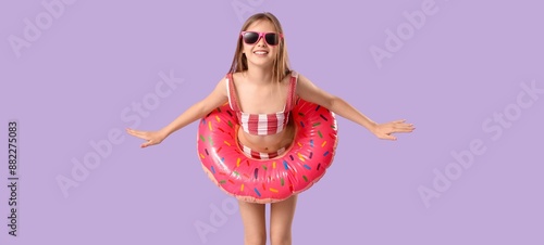 Foto Cute little girl in swimsuit and with inflatable ring on lilac background