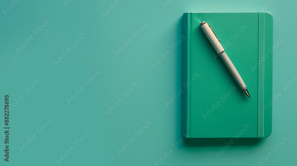 Notebook with pen on a teal background Notebook with pen on a teal background