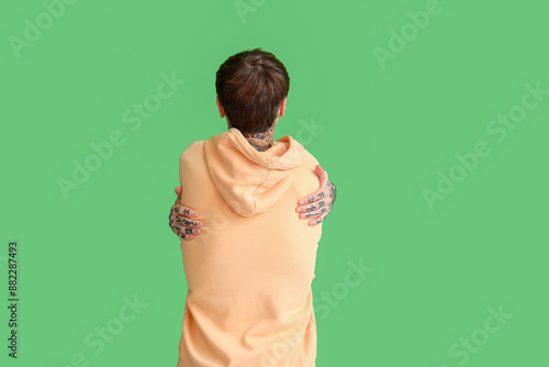 Young man hugging himself o...