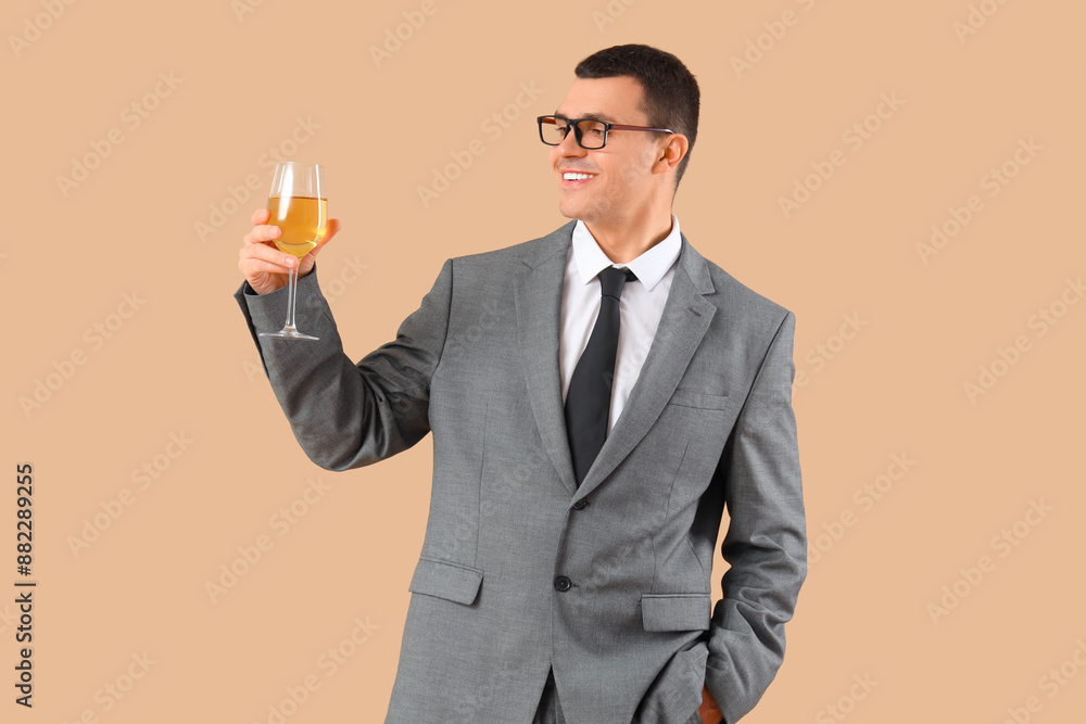 Young businessman with glass of wine on beige background Young businessman with glass of wine on beige background
