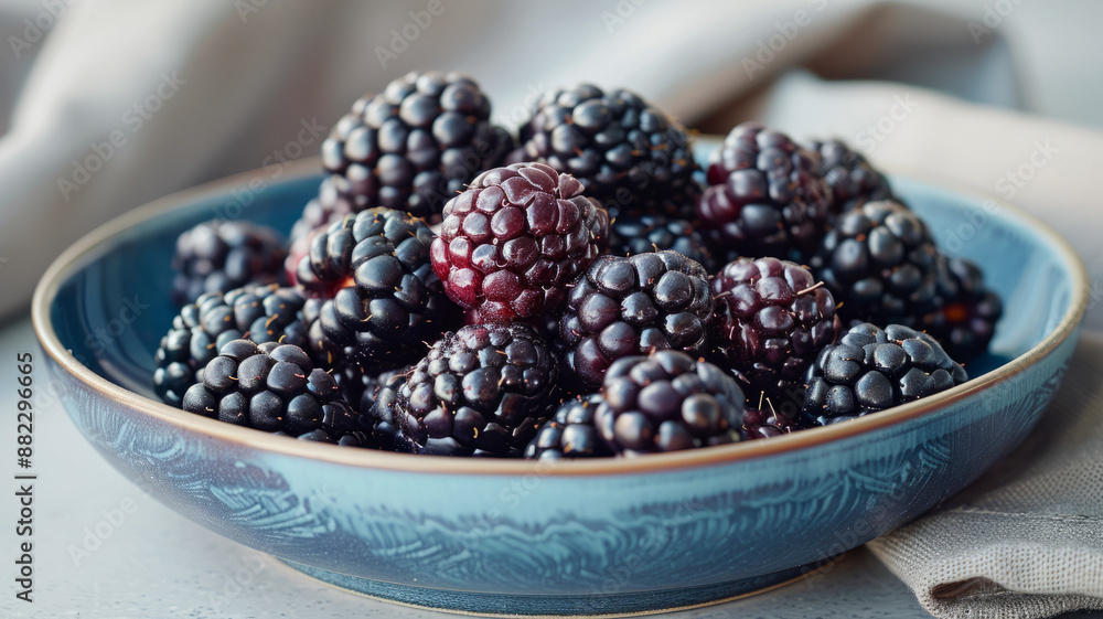 Bowl of fresh blackberries on a light surface. Bowl of fresh blackberries on a light surface.