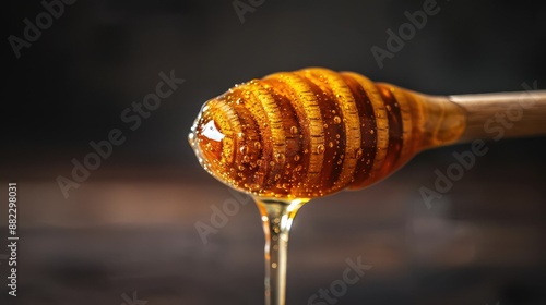 Golden honey dripping from a wooden dipper