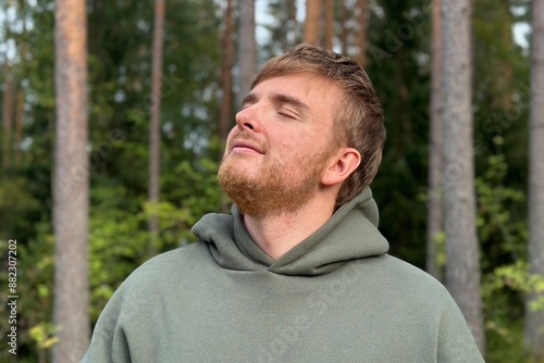 young man relax and deep breath in forest or park at warm weather 