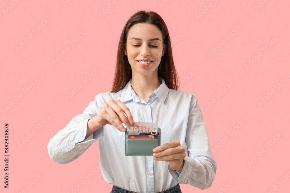 Young woman with credit card holder on pink background Young woman with credit card holder on pink background