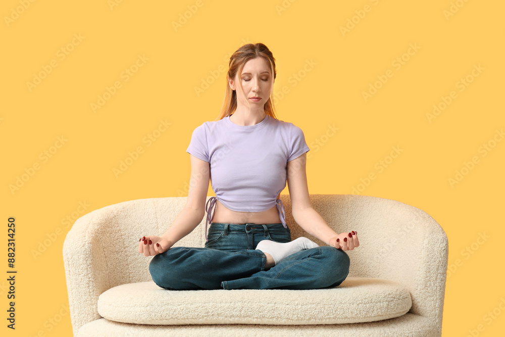 Beautiful young woman practicing yoga on sofa near color wall Beautiful young woman practicing yoga on sofa near color wall