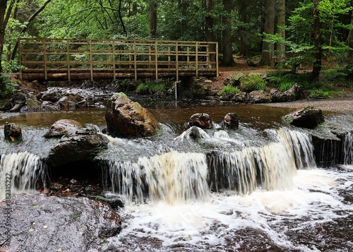 Waterfall in river Hoegne in Jalhay, Ardennes, Belgium. Wooden bridge as a river crossing. photo