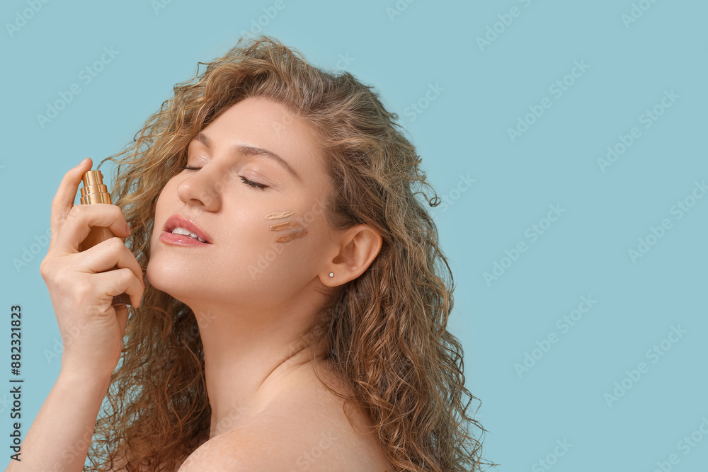 Beautiful young woman with bottle of makeup foundation on blue background Beautiful young woman with bottle of makeup foundation on blue background