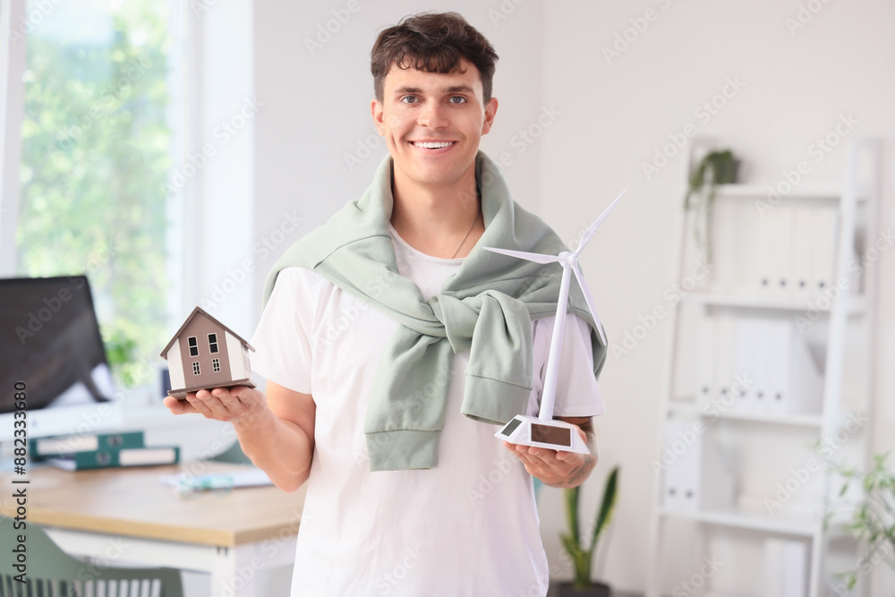 Male engineer with wind turbine and house model in office Male engineer with wind turbine and house model in office