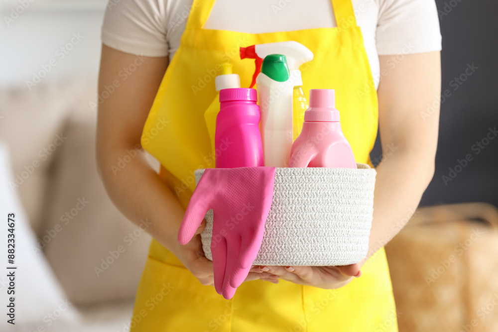 Female janitor with basket of cleaning supplies in room, closeup Female janitor with basket of cleaning supplies in room, closeup