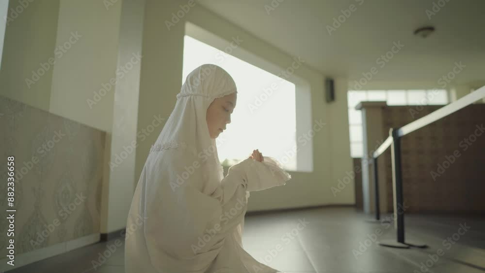 an asian muslim woman is raising her hands and praying to allah in the mosque in the afternoon. he increased his worship during the month of Ramadan an asian muslim woman is raising her hands and praying to allah in the mosque in the afternoon. he increased his worship during the month of Ramadan