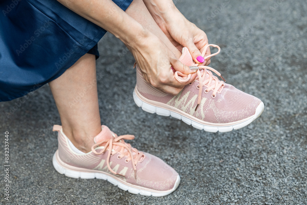 woman tying laces on sneakers while sitting on a bench. man tying shoelaces in the park. tying shoelaces with a bow. woman in skirt and sneakers. woman tying laces on sneakers while sitting on a bench. man tying shoelaces in the park. tying shoelaces with a bow. woman in skirt and sneakers.