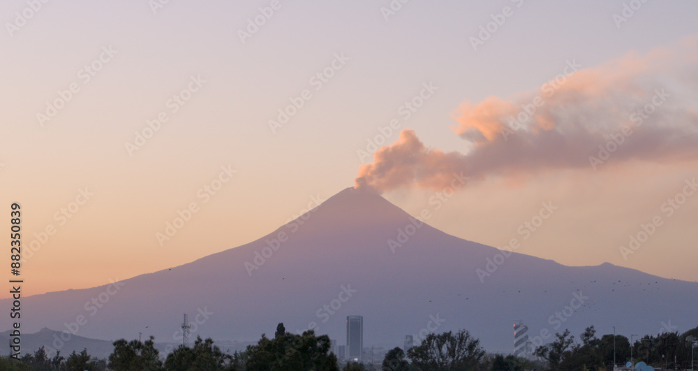 Εκτύπωση καμβά Popocatepetl volcano and city at sunset with pink and purple  colors and eruptin