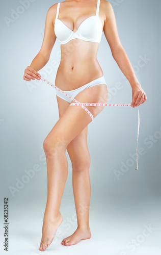 Leg, tape measure and woman in studio for weight loss, healthy diet or fitness with gray background. Underwear, wellness and hands of model for results in exercise, transformation or body goals