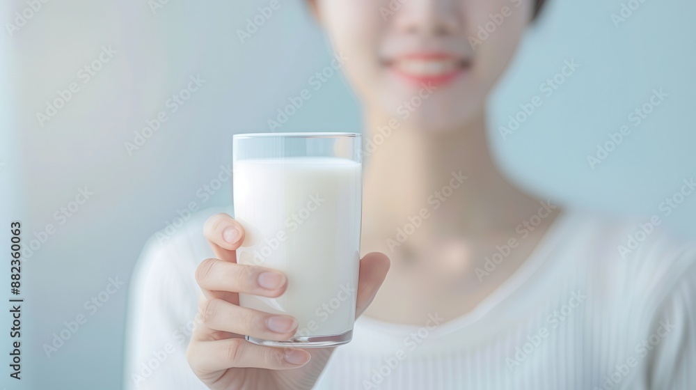A woman is holding a glass of milk and smiling A woman is holding a glass of milk and smiling