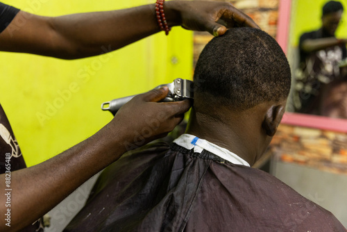 Fotografie A man is getting his hair cut by a barber in Africa