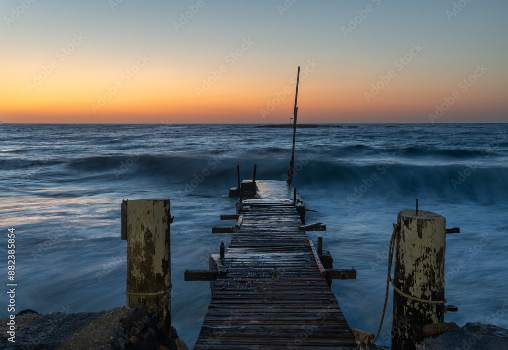 Obraz premium Old wooden bridge into the sea with a beautiful sunset