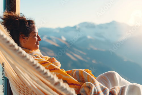 Woman relaxes in a hammock with a view of snow-capped mountains