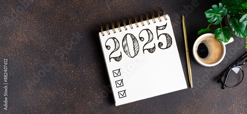 New year resolutions 2025 on desk. 2025 resolutions list with notebook, coffee cup on table. Goals, resolutions, plan, action, checklist concept. New Year 2025 template, copy space photo