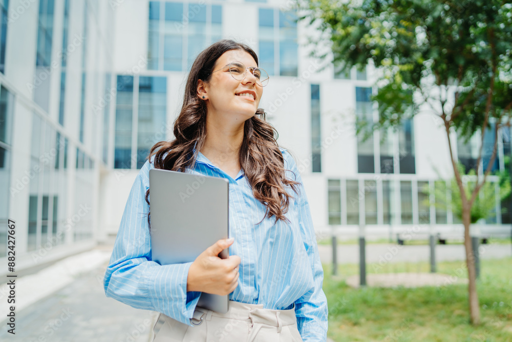 One beautiful young successful business woman going to work at business office modern building while holding laptop and wearing glasses	