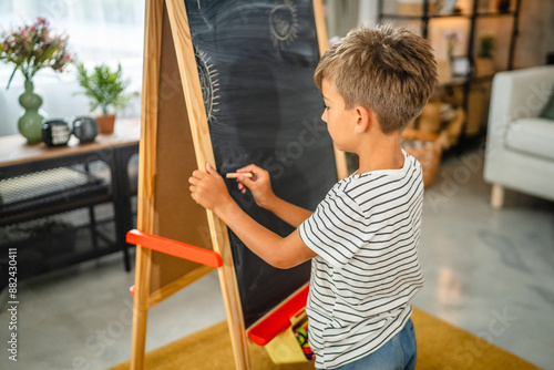 Young boy draw on blackboard whit chalk in the living room